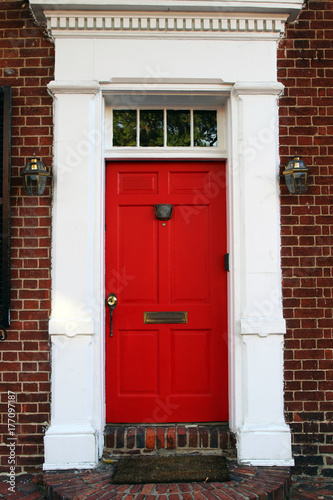 A red front door of a Colonial style house.