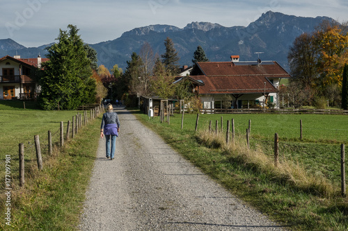 Hiker walking through the meadows and into a village in the Bavarian foothills in Germany