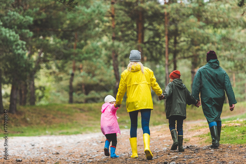 Photos family in raincoats walking in forest