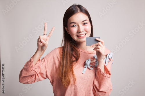 Young Asian woman show Victory with a blank card.