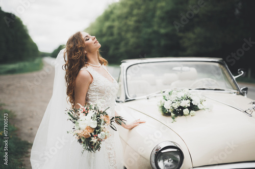 Fotografia Happy bride in the retro car posing on her weeding day
