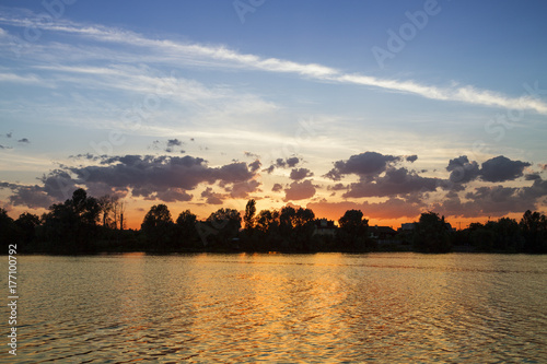 Sunset and water. Golden landscape. Sky, clouds, sun and sunset water with golden reflections. Gold water with small waves.