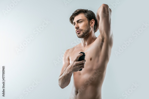 shirtless man spraying deodorant