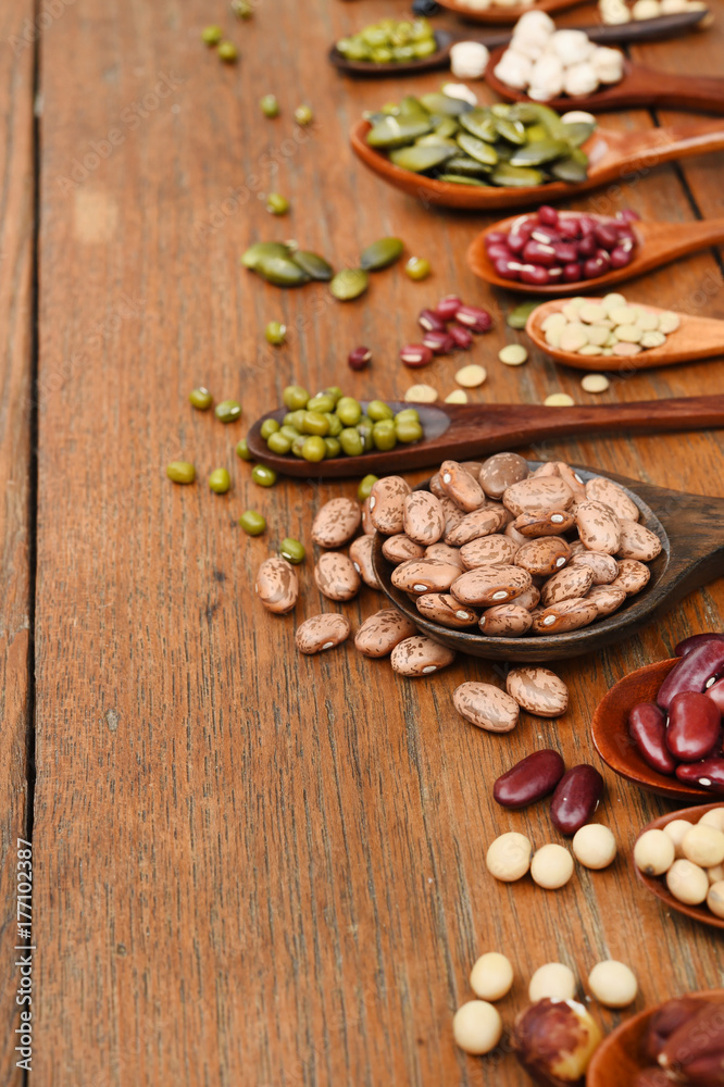 Assortment of beans and lentils in wooden spoon on teak wood background Assortment of beans and lentils in wooden spoon on teak wood background