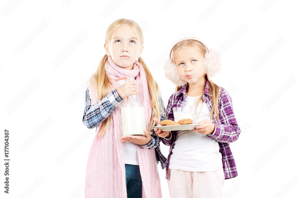 Portrait of two little sisters wearing scarf and earmuffs posing against white background