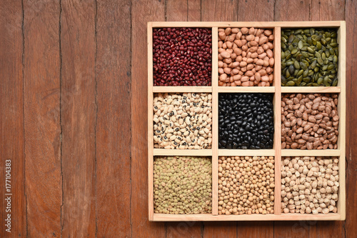 Assortment of beans and lentils in wooden spoon on teak wood background © thananya_k