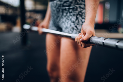 Close-Up of girl doing workout with barbell in Gym photo