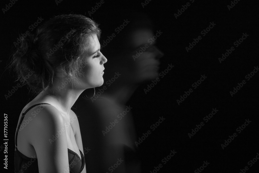 Naklejka premium beautiful young woman and her blurred silhouette on black background with copy space, monochrome