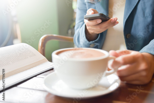 Woman Hands using smart phone and holding a cup of coffee.