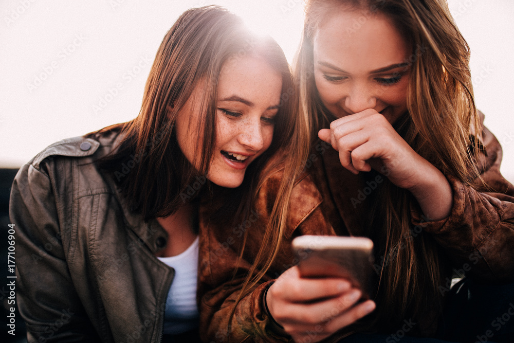 Happy Teenager girls using smart phone looking at pictures Happy Teenager girls using smart phone looking at pictures