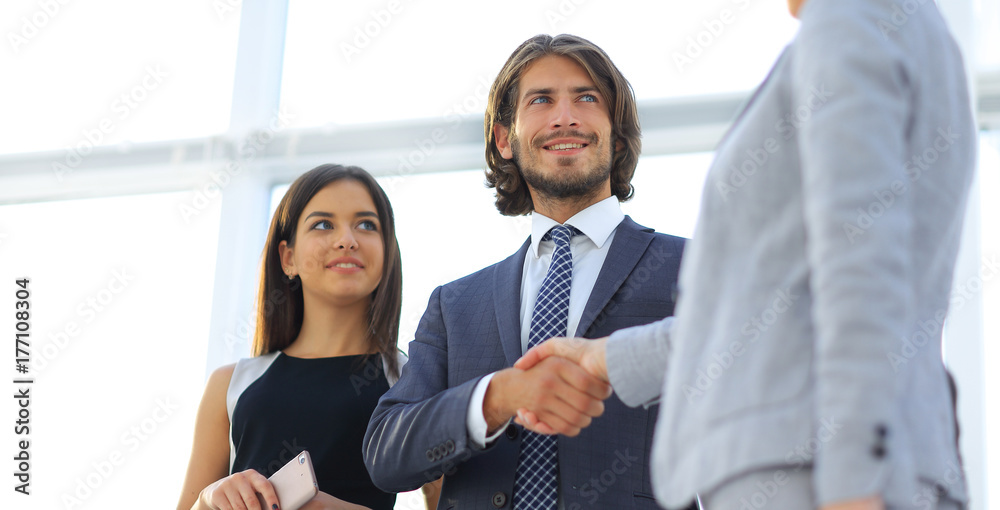 Businesspeople shaking hands against room with large window loo Businesspeople shaking hands against room with large window loo