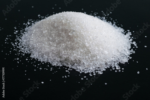 Heap of granulated sugar isolated on black
