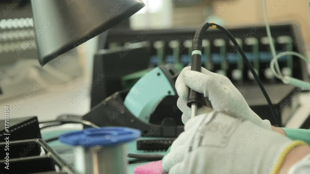 Woman holding pincette and soldering iron install electronic components on PCB (Printed circuit boards) Woman holding pincette and soldering iron install electronic components on PCB (Printed circuit boards)