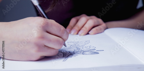 Female artist designer draws a pencil sketch of flowers. Close up. (creativity, art, training concept)