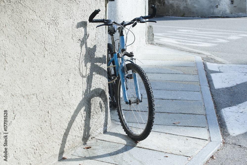 bicicletta appogita al muro sul pavemento ombra della ruota a forma di cuore
