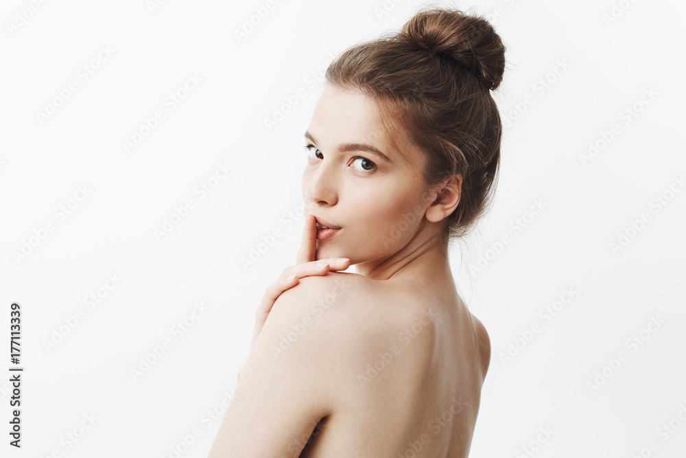 Charming sexy good-looking young caucasian woman with brown hair in fashionable hairstyle and naked body, holding finger in front of lips, looking in camera in three quoters with flirty face Charming sexy good-looking young caucasian woman with brown hair in fashionable hairstyle and naked body, holding finger in front of lips, looking in camera in three quoters with flirty face