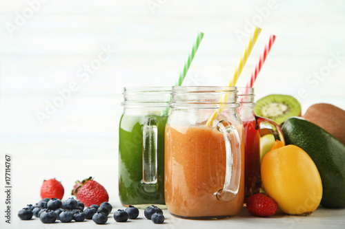 Sweet smoothie in glass jars with fruits on white background