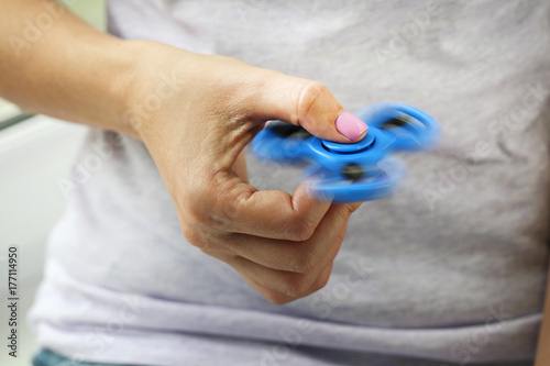 Female hand holding blue fidget spinner toy