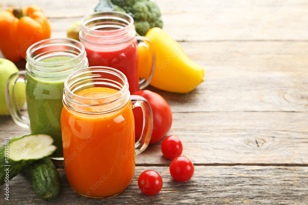 Vegetables smoothie in jars on wooden table Vegetables smoothie in jars on wooden table