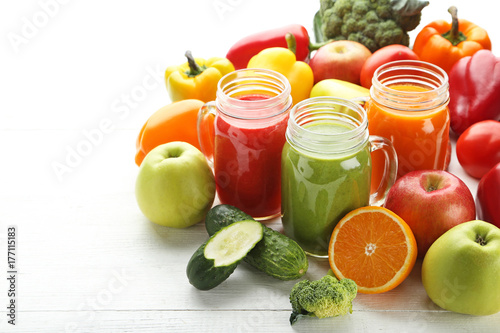 Vegetables smoothie in jars on white wooden table