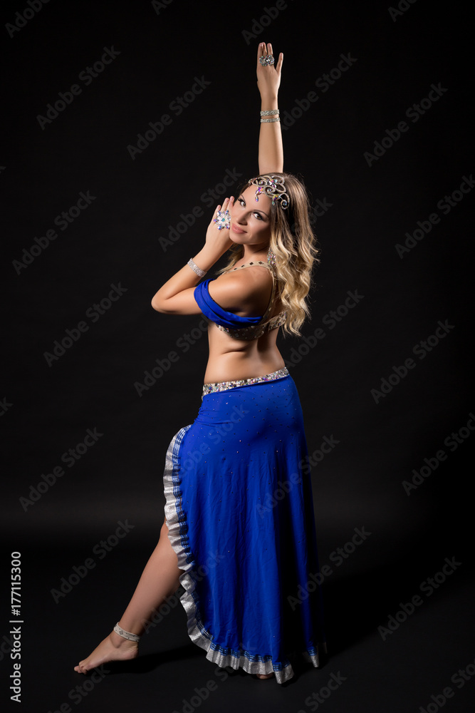 Beautiful belly dancer performing belly dance on black background.
