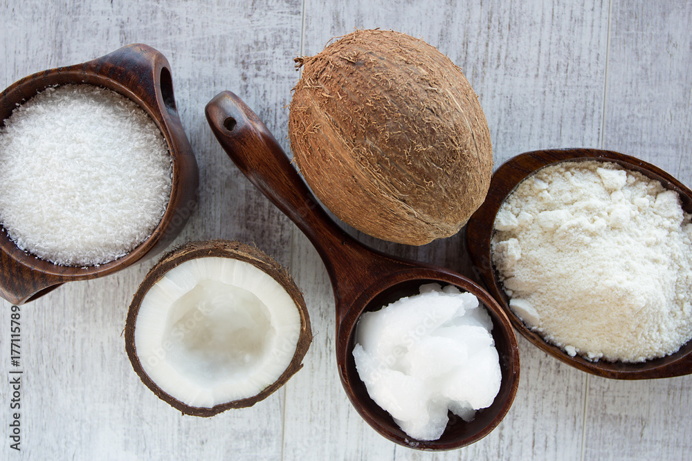 Homemade coconut products on wooden table background. Coconut oil, coconut flour and shredded coconut Homemade coconut products on wooden table background. Coconut oil, coconut flour and shredded coconut