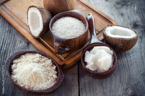 Homemade coconut products on wooden table background. Coconut oil, coconut flour and shredded coconut