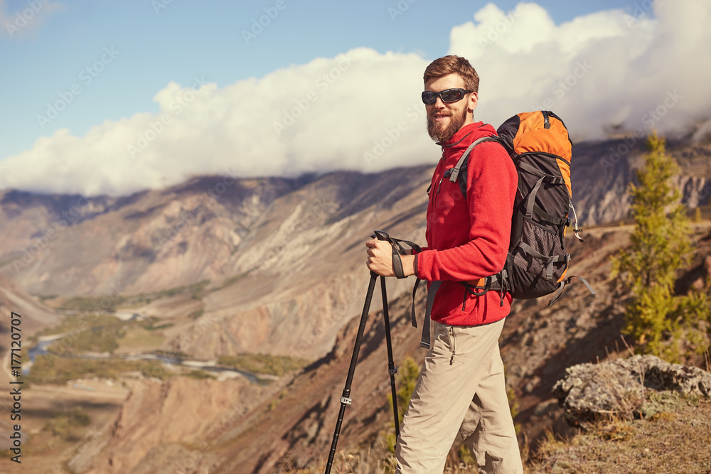 Handsome young bearded male hiker standing on the edge of a canyon looking away