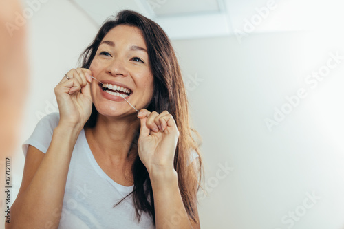 Reflection of woman using dental floss photo