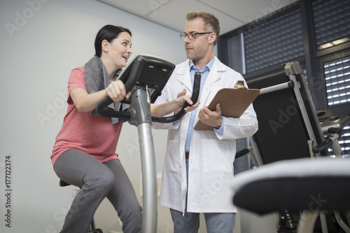 Doctor talking to patient on exercise machine