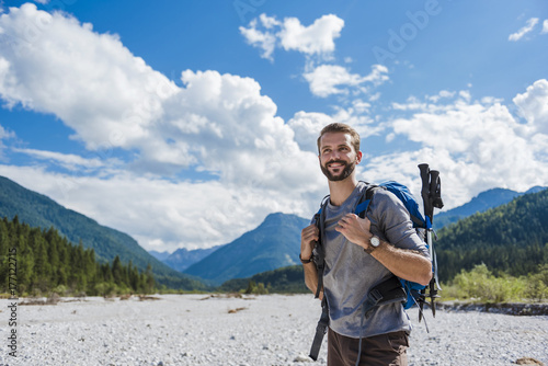 Germany, Bavaria, portrait of young hiker with backpack and hiking poles