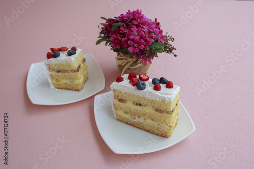 a piece of cake with blueberries and raspberries is on the table with a pink color