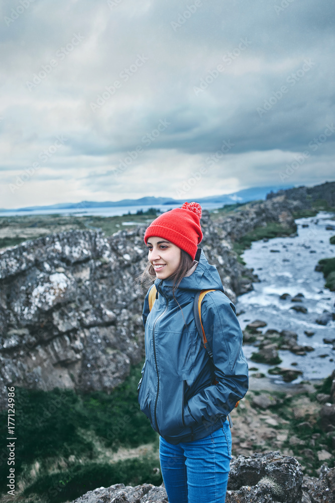 young woman hiker walking in beautiful mountains in Thingvellir valley, Iceland