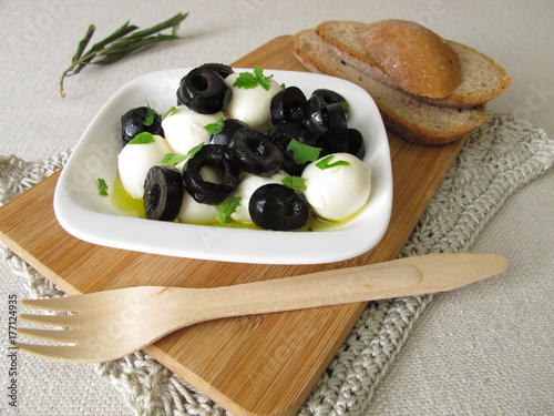 Marinierter Mozzarella mit schwarzen Oliven, Olivenöl und Blattsenf photo