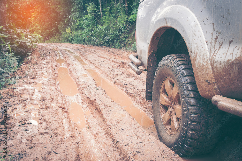 Car wheel on a dirt road. Off-road tire covered with mud, dirt terrain. Outdoor, adventures and travel. Car tire close-up in a countryside landscape with a muddy road. Four wheel truck in mud. Car wheel on a dirt road. Off-road tire covered with mud, dirt terrain. Outdoor, adventures and travel. Car tire close-up in a countryside landscape with a muddy road. Four wheel truck in mud.