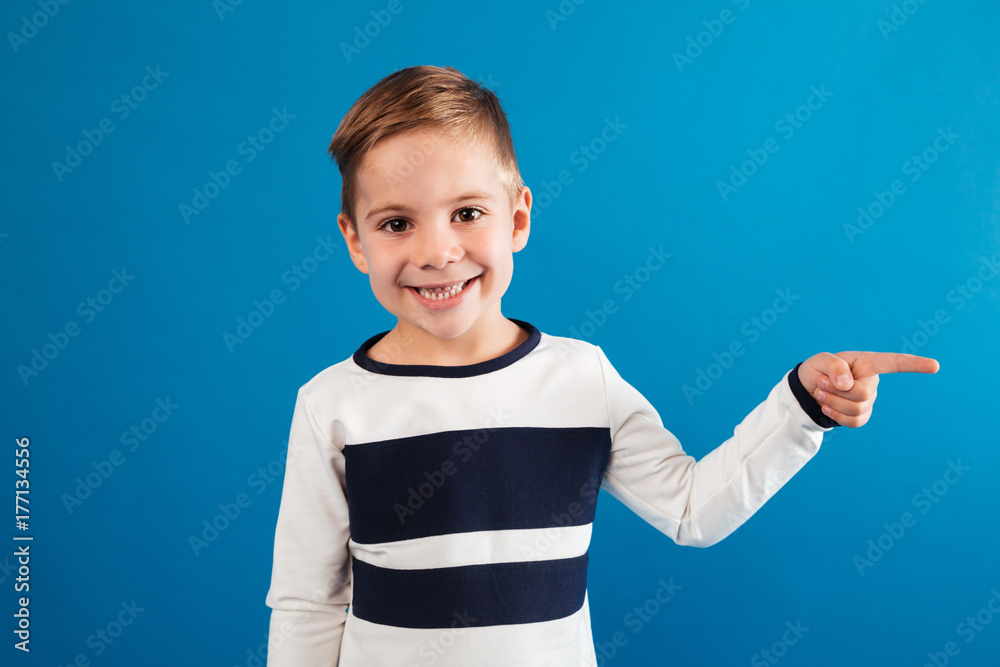 Smiling young boy in sweater pointing away Smiling young boy in sweater pointing away