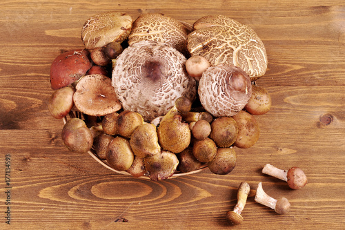 forest mushrooms in a wicker plate on a wooden background.