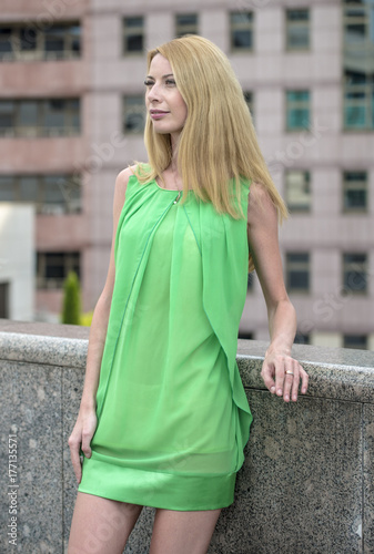   Beautiful blonde girl in a green short summer dress on the streets of the city   © rogkoff