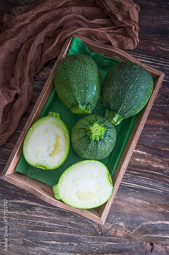 Green round zucchini on an old wooden background. Rustic style. Top view