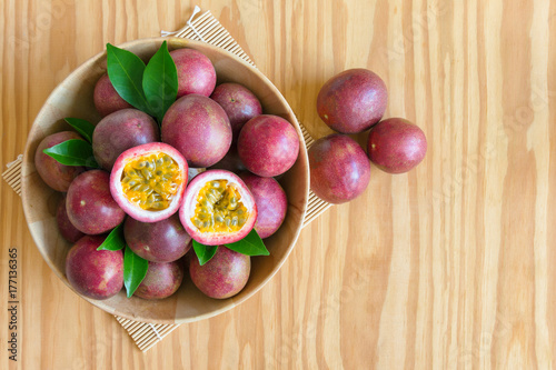 Fresh passion fruit in wood bowl on wood table in top view flat lay with copy space for background or wallpaper. Ripe passion fruit so sweet and sour. Tropical fruit.