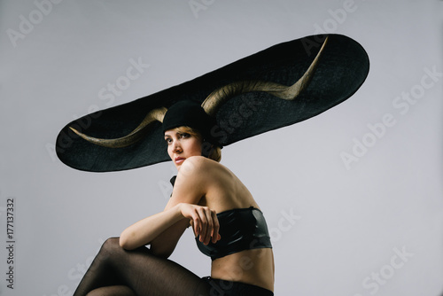 Portrait of a feminine fashion model wearing extravagant hat with horns photo