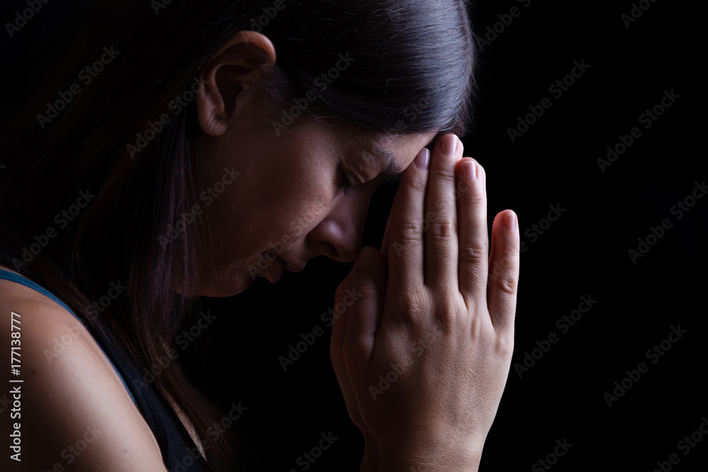 Faithful woman praying, with hands folded in worship touching the forehead, head down and eyes closed in religious fervor, on black background. Concept for religion, faith, prayer and spirituality.
Faithful woman praying, with hands folded in worship touching the forehead, head down and eyes closed in religious fervor, on black background. Concept for religion, faith, prayer and spirituality.