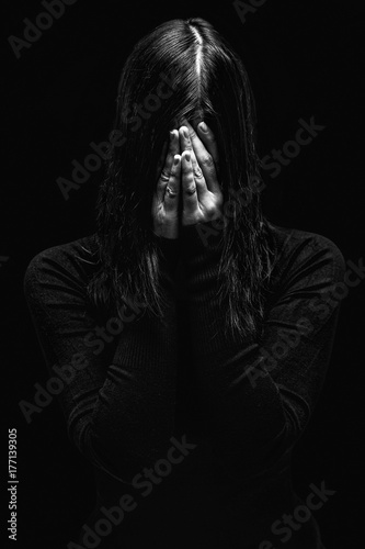 Fotografía Emotional woman crying and covering the face with the hands hiding the tears, on a black or dark background