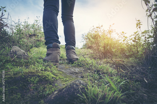 View of hiker legs walking on a path. Active woman backpacker traveling on the nature.