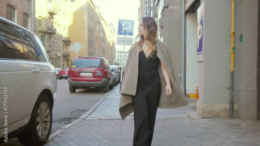 Gorgeous girl goes along a city street dressed in a fashionable style happily in slo-mo Gorgeous girl goes along a city street dressed in a fashionable style happily in slo-mo