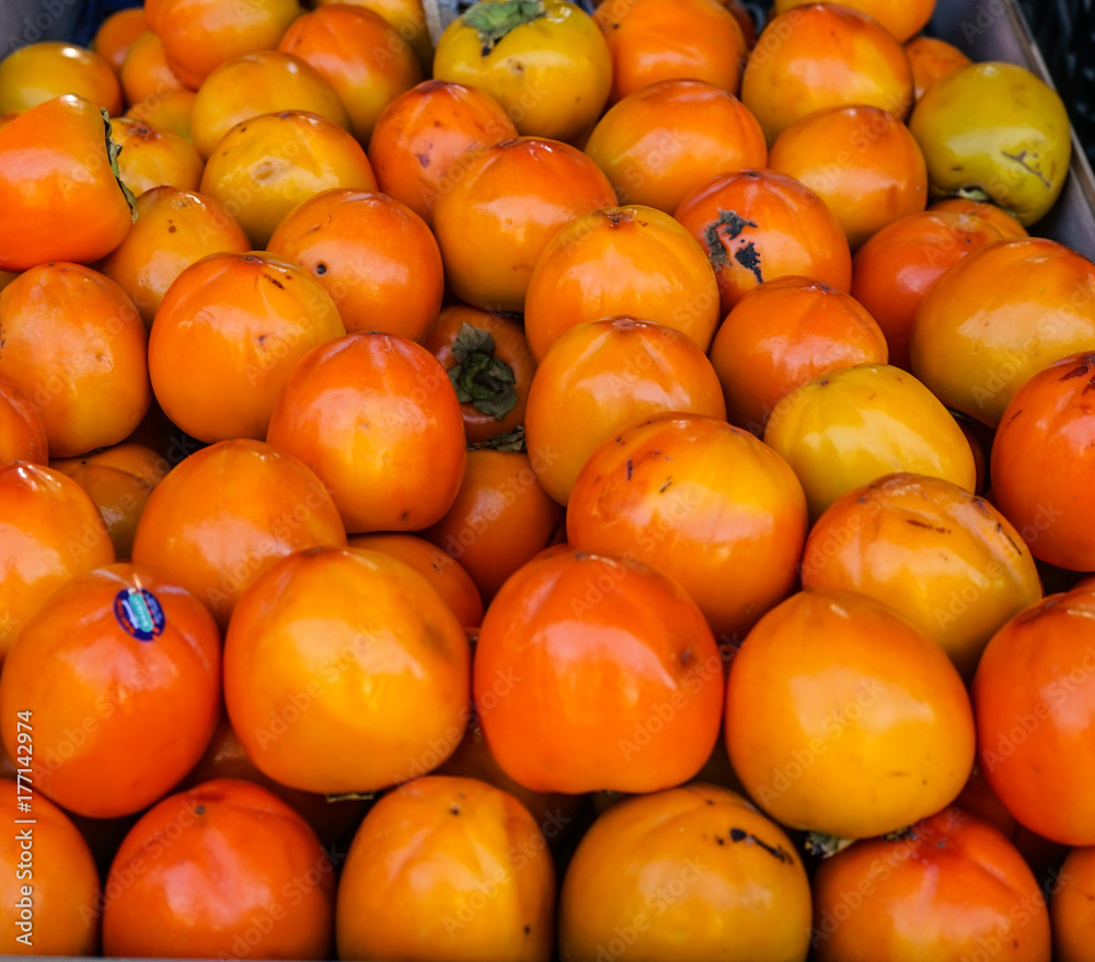 Persimmons in stack in a vegetables stand in a street market in Madrid, Spain.