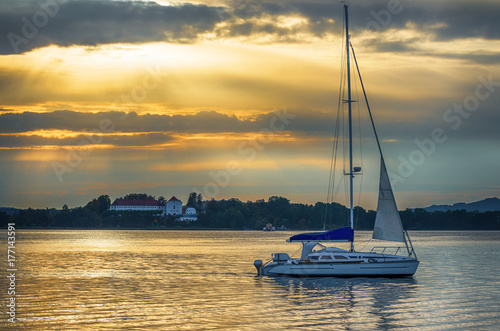 Yacht sailing at sunset.Boat sailing in a lake with golden sunset and cloudscape background. Chiemsee Lake, Bavaria, Germany