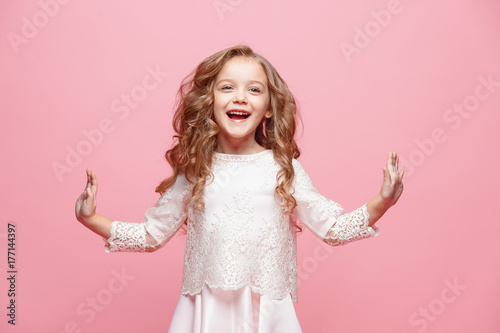 The beautiful little girl in dress standing and posing over white background