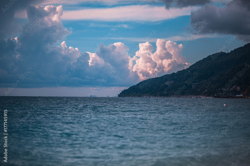 Sea and mountains against a background of blue clouds