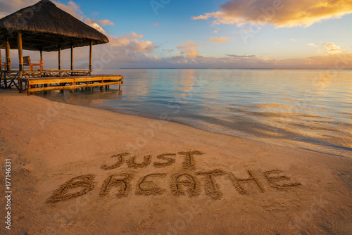 Fotografie Foreground written in the sand just breathe at sunset in Mauritius Island with Jetty on the left side